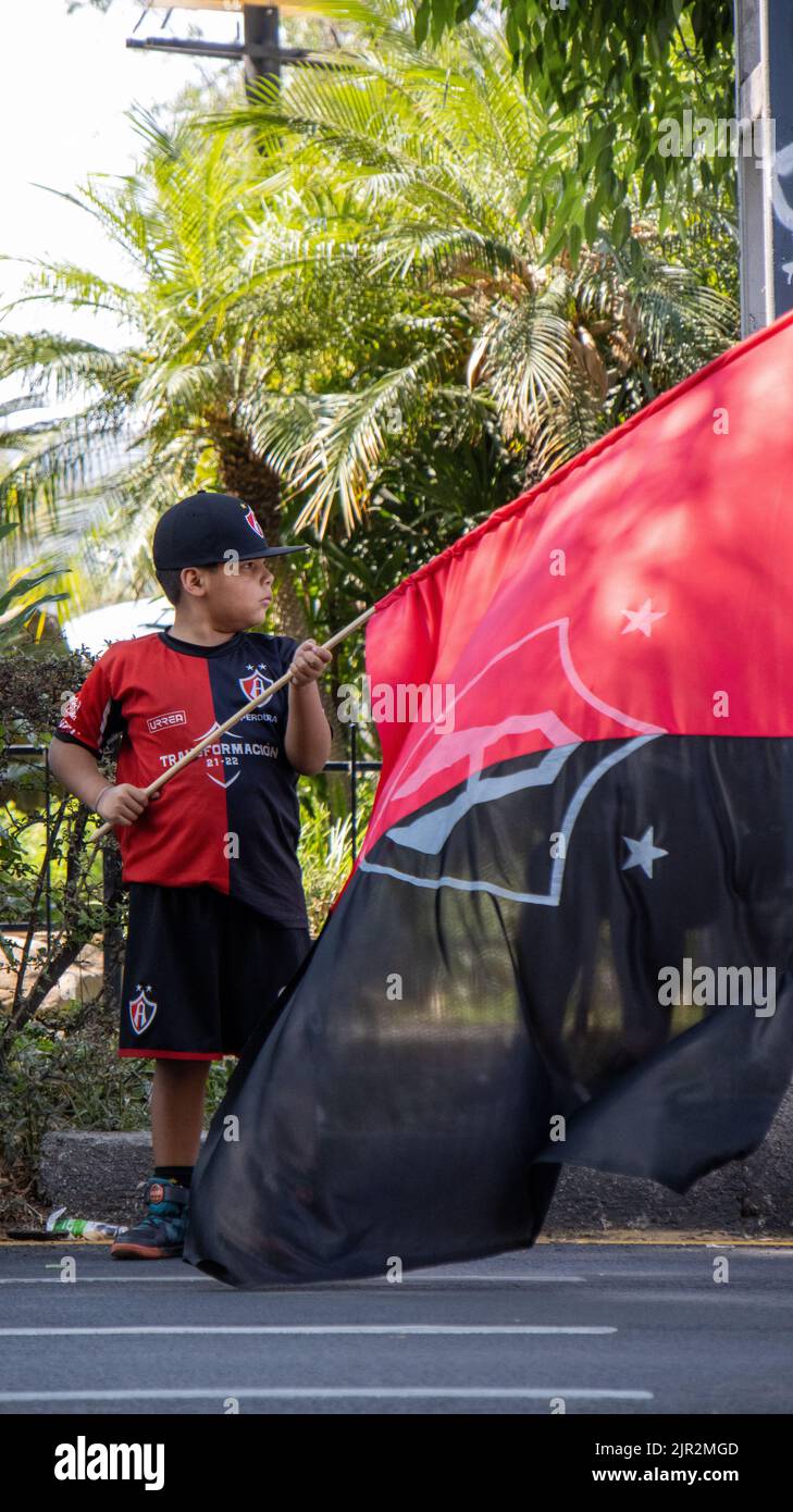 A young Atlas Soccer Football fan awaiting the Atlas Championship Parade with a flag in Guadalajara, Mexico Stock Photo