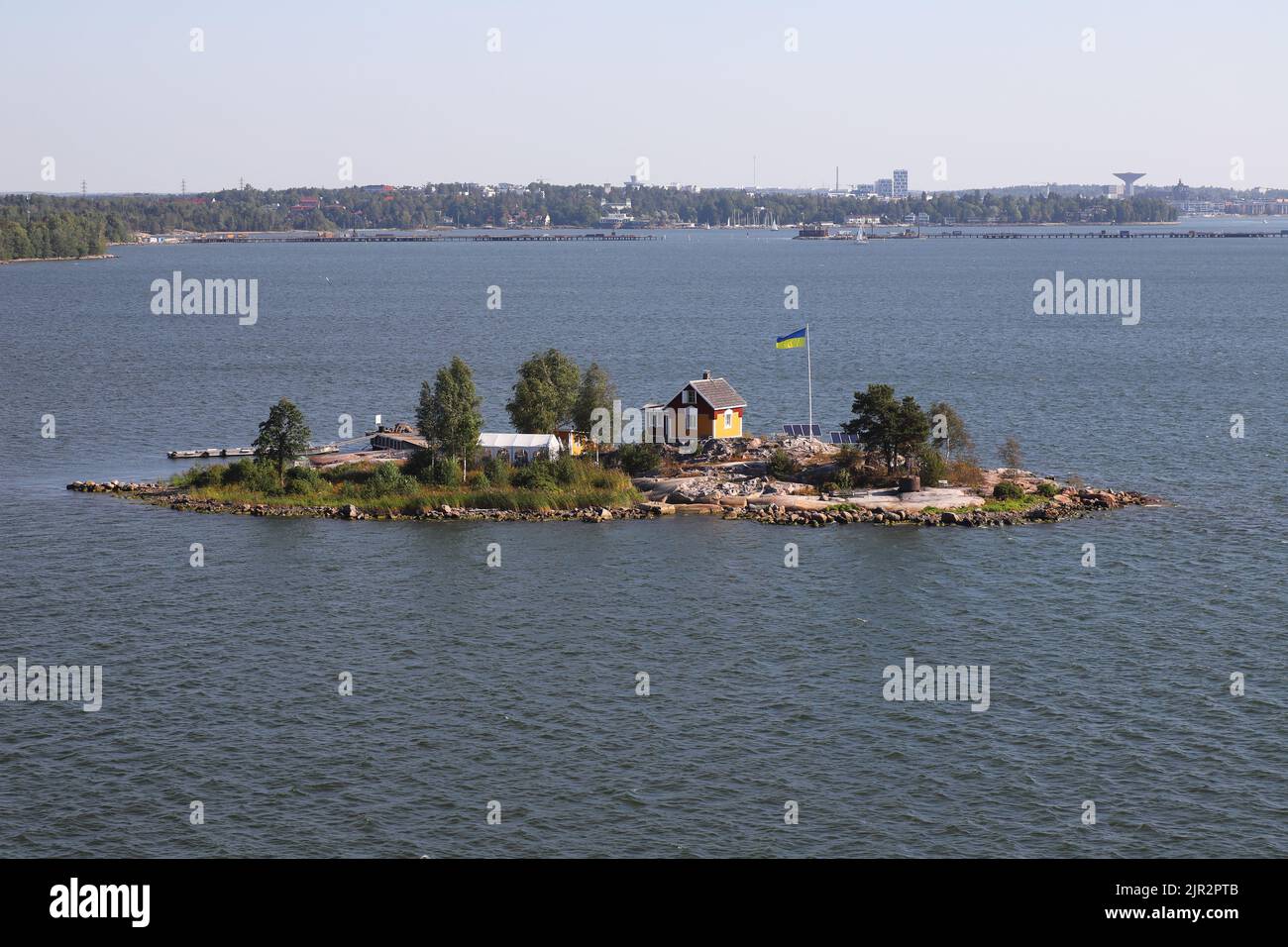 Helsinki, Finland - August 20, 2022: The Ukrainian flag raised next to a small house on a small island arriving ship in the Helsinki harbor entrance. Stock Photo