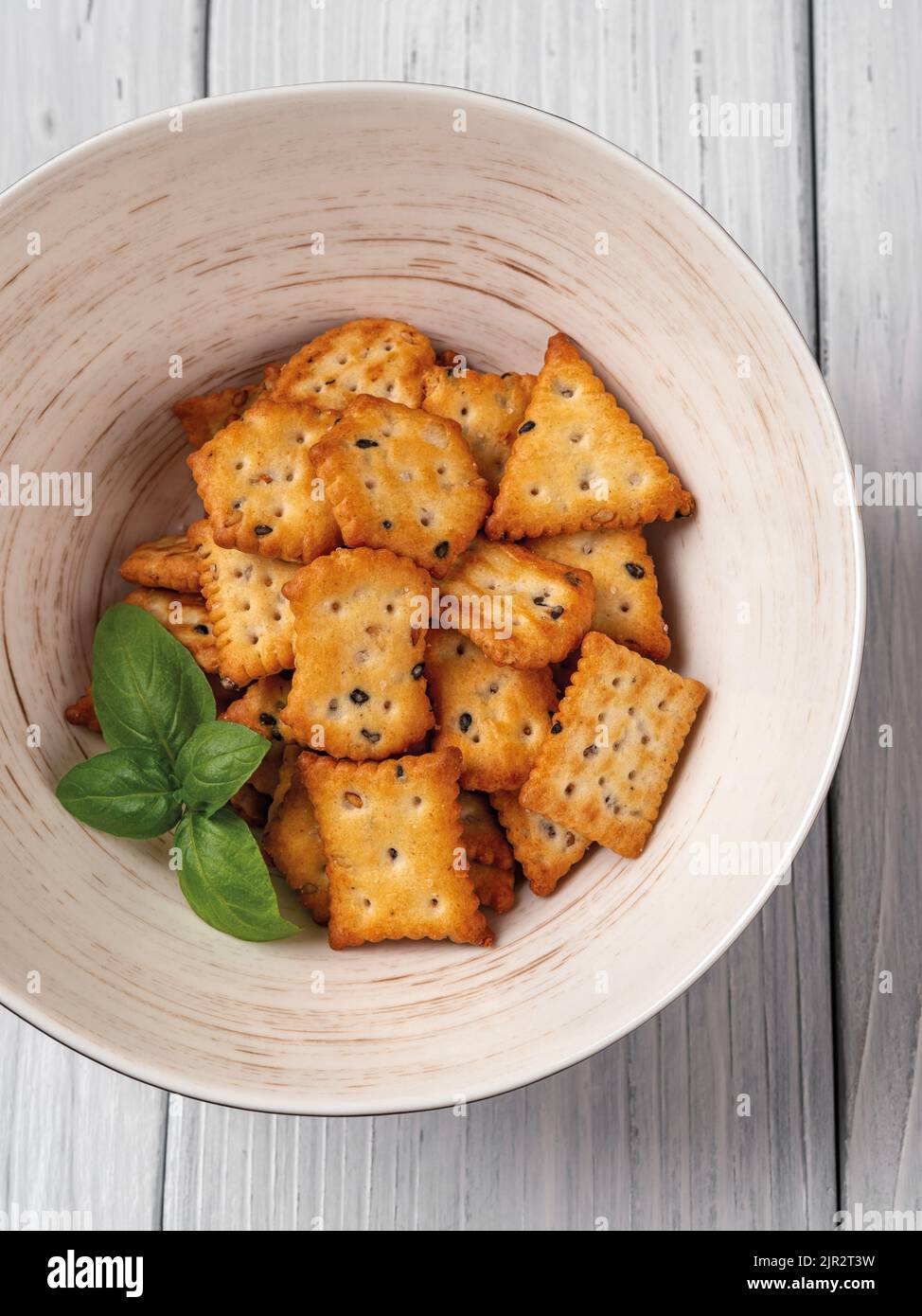 Some saltine crackers in a bowl on a white wood background. Ready to