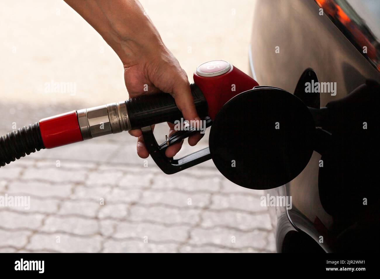 Man's hand is inserting a gas pump nozzle in a fuel tank, Car refueling