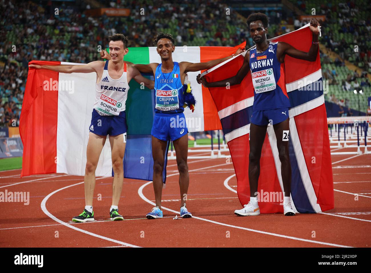 2022 European Championships - Athletics - Olympiastadion, Munich, Germany - August 21, 2022 Italy's Yemaneberhan Crippa celebrates after winning gold in the men's 10,000m final alongside silver medallist Norway's Zerei Kbrom Mezngi and bronze medallist France's Yann Schrub REUTERS/Wolfgang Rattay Stock Photo