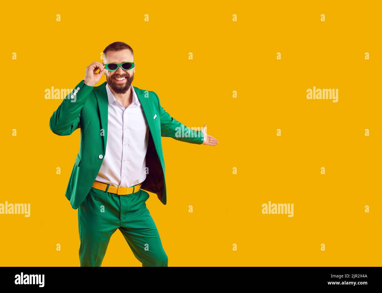 Happy man in green suit isolated on yellow copy space background invites you to Patrick's Day Stock Photo