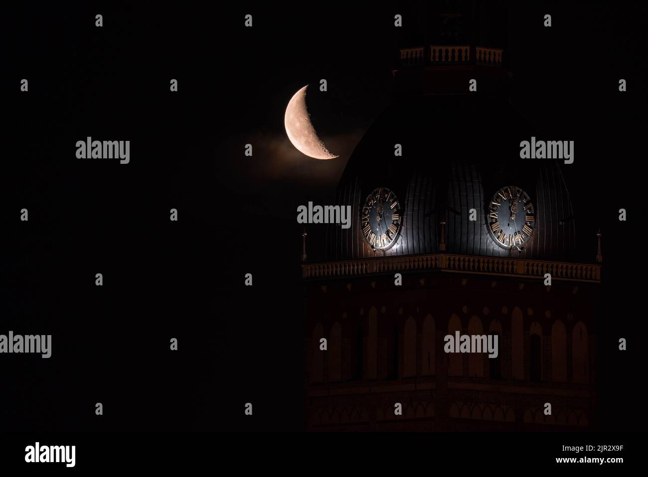 Beautiful quarter moon over Riga old town behind Domes cathedral clock.  Stock Photo