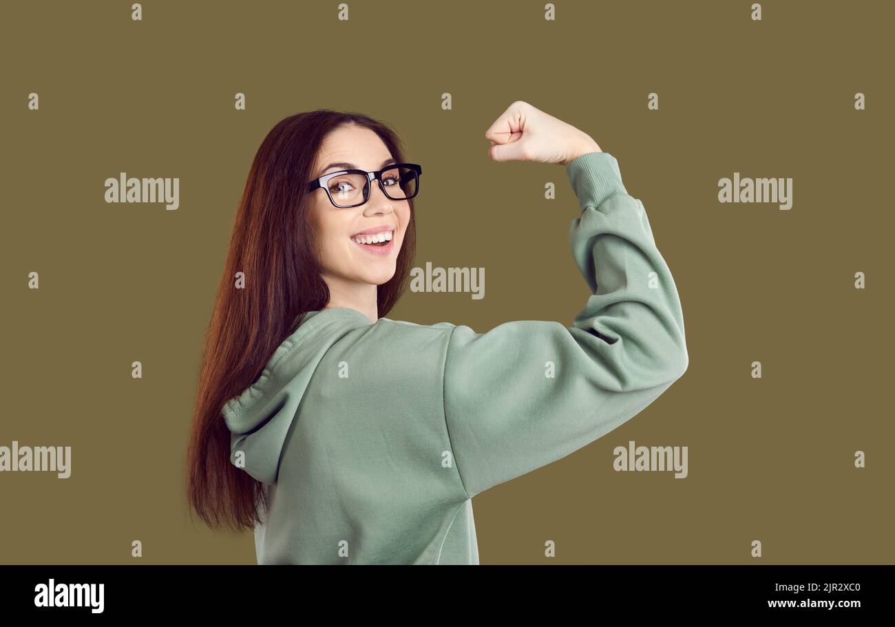 Happy smiling confident young student girl flexing her arm and showing her power Stock Photo