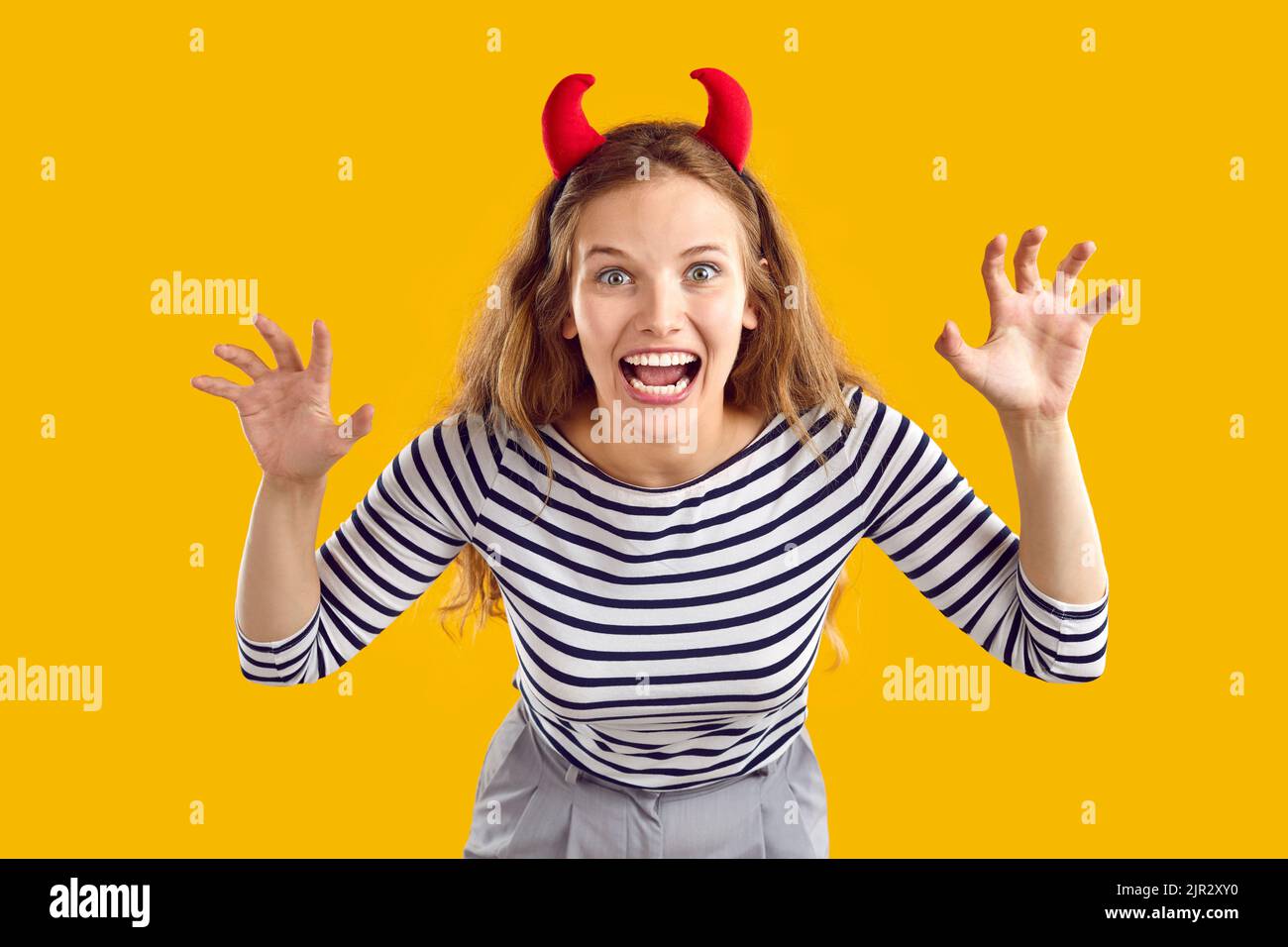 Studio portrait of happy funny young girl wearing devil horns as her