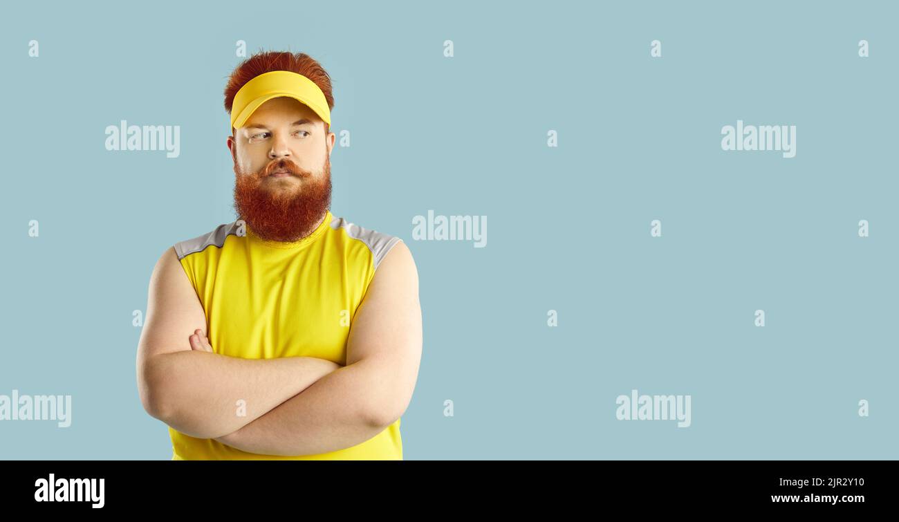Fat man standing on blue copy space background and thinking about his fitness workouts Stock Photo