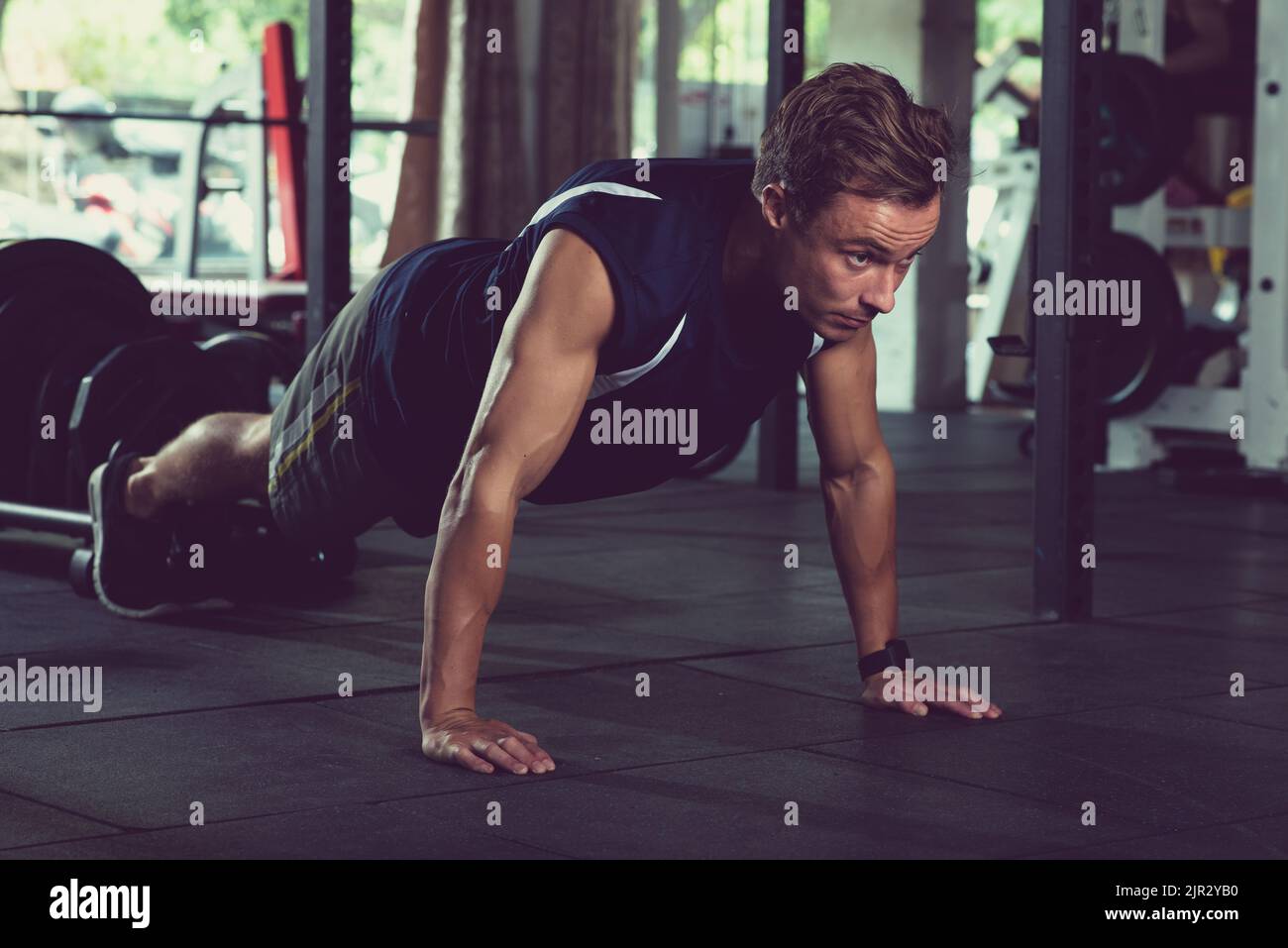 Fit young man doing push-ups in gym Stock Photo