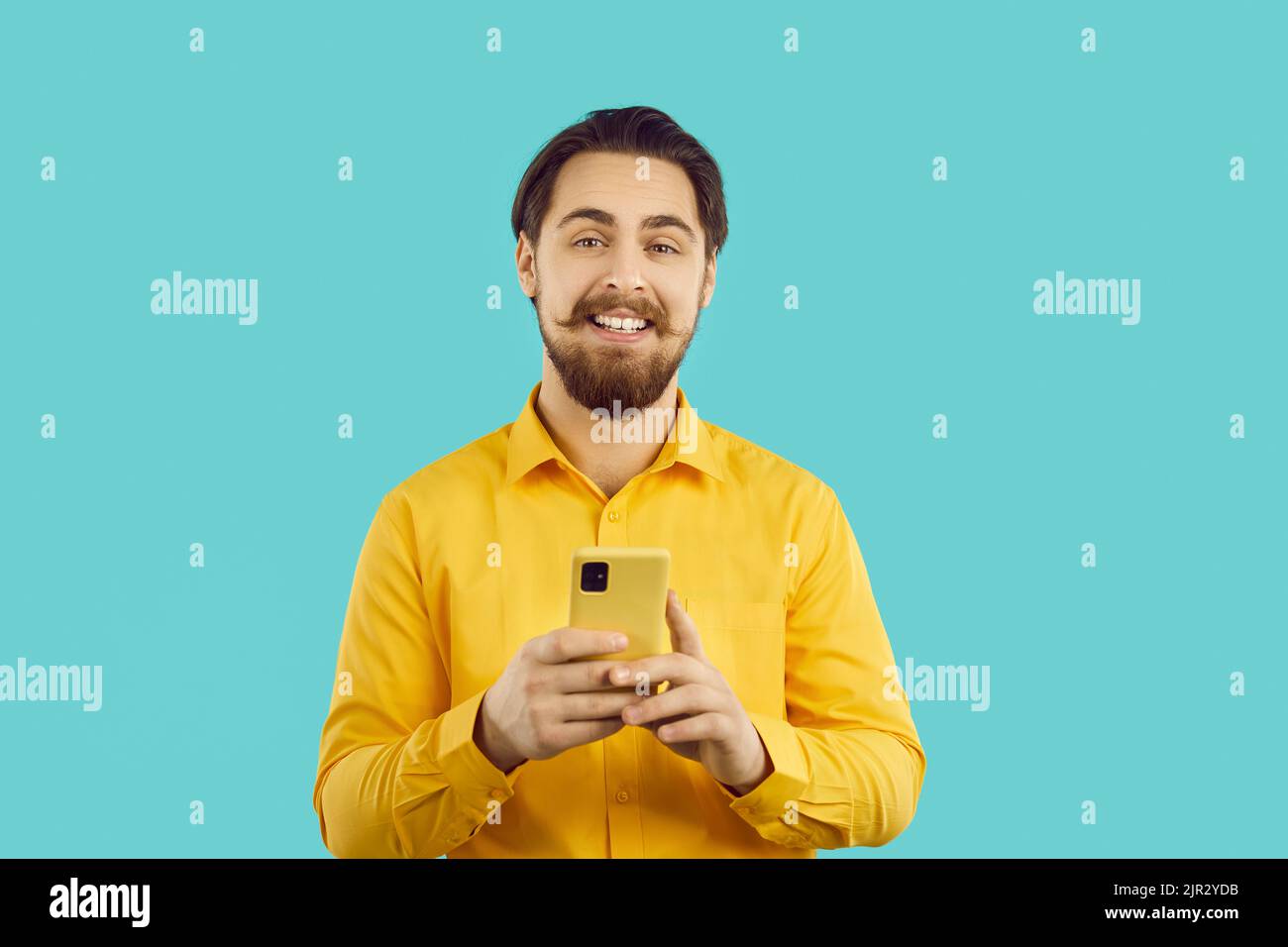 Happily satisfied handsome man uses mobile phone for online shopping, chatting or using service apps Stock Photo