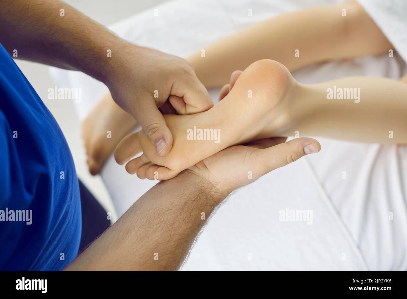 Reflexologist and acupressure therapy professional doing foot massage to young woman Stock Photo