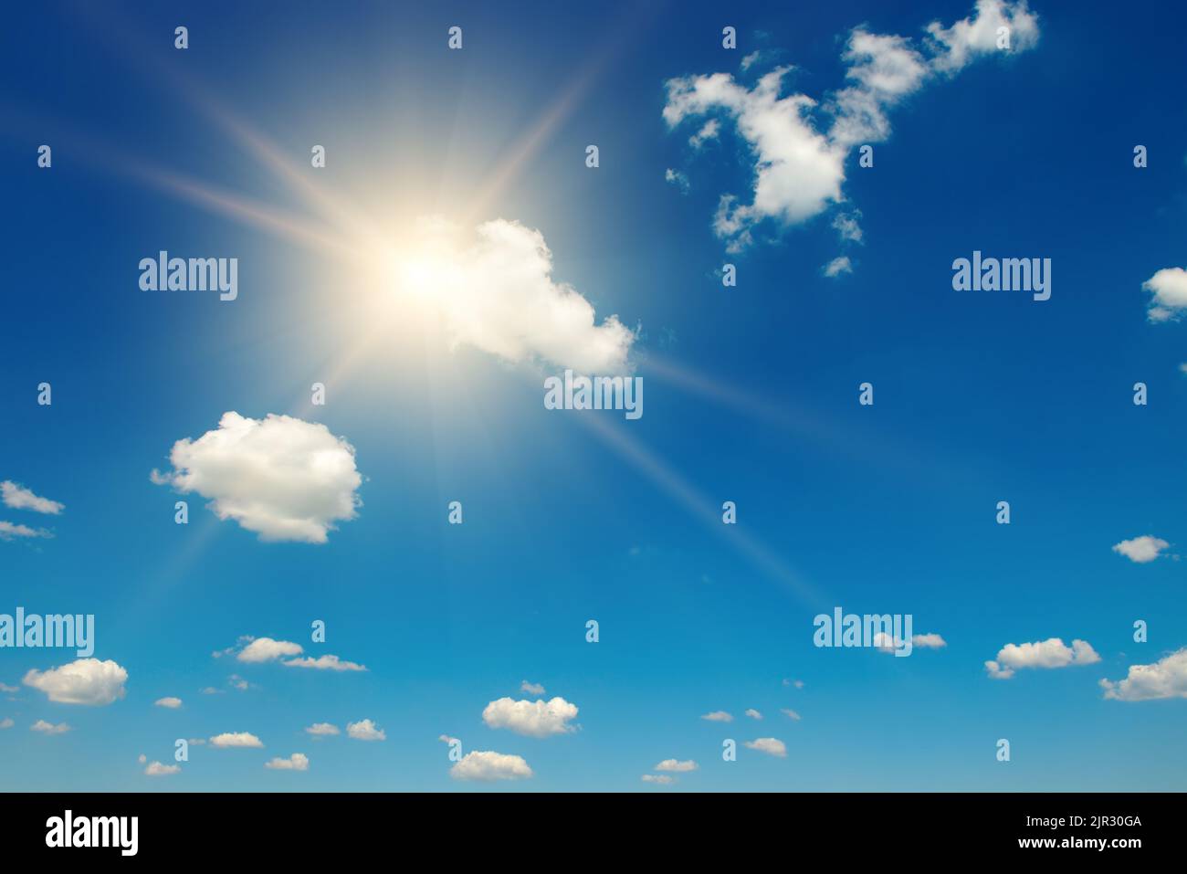 Blue sky with white fluffy clouds and bright sun with rays Stock Photo ...