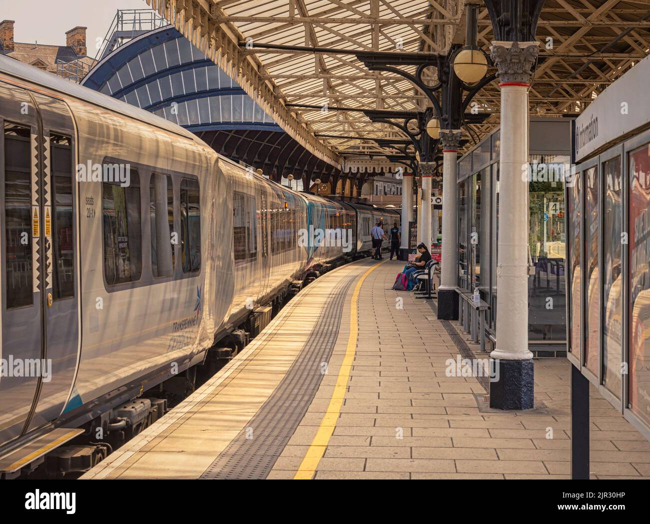 A train rests beside a railway station platform. A historic 19th ...