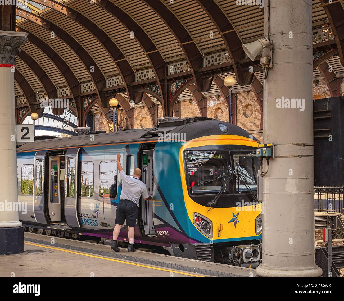 A train rests beside a railway station platform under a historic ...