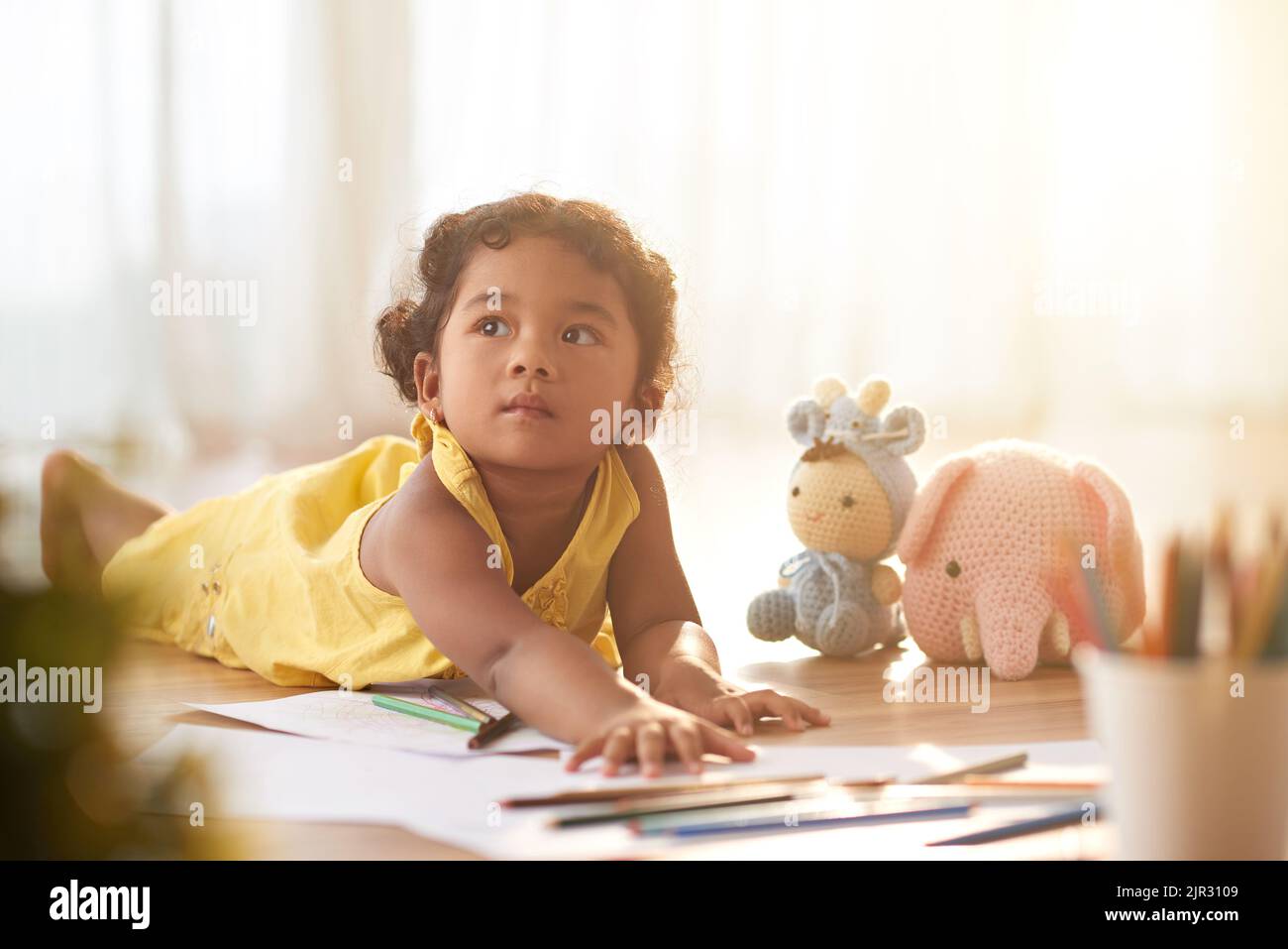 Dreamy little girl lying on the floor in nursery Stock Photo Alamy