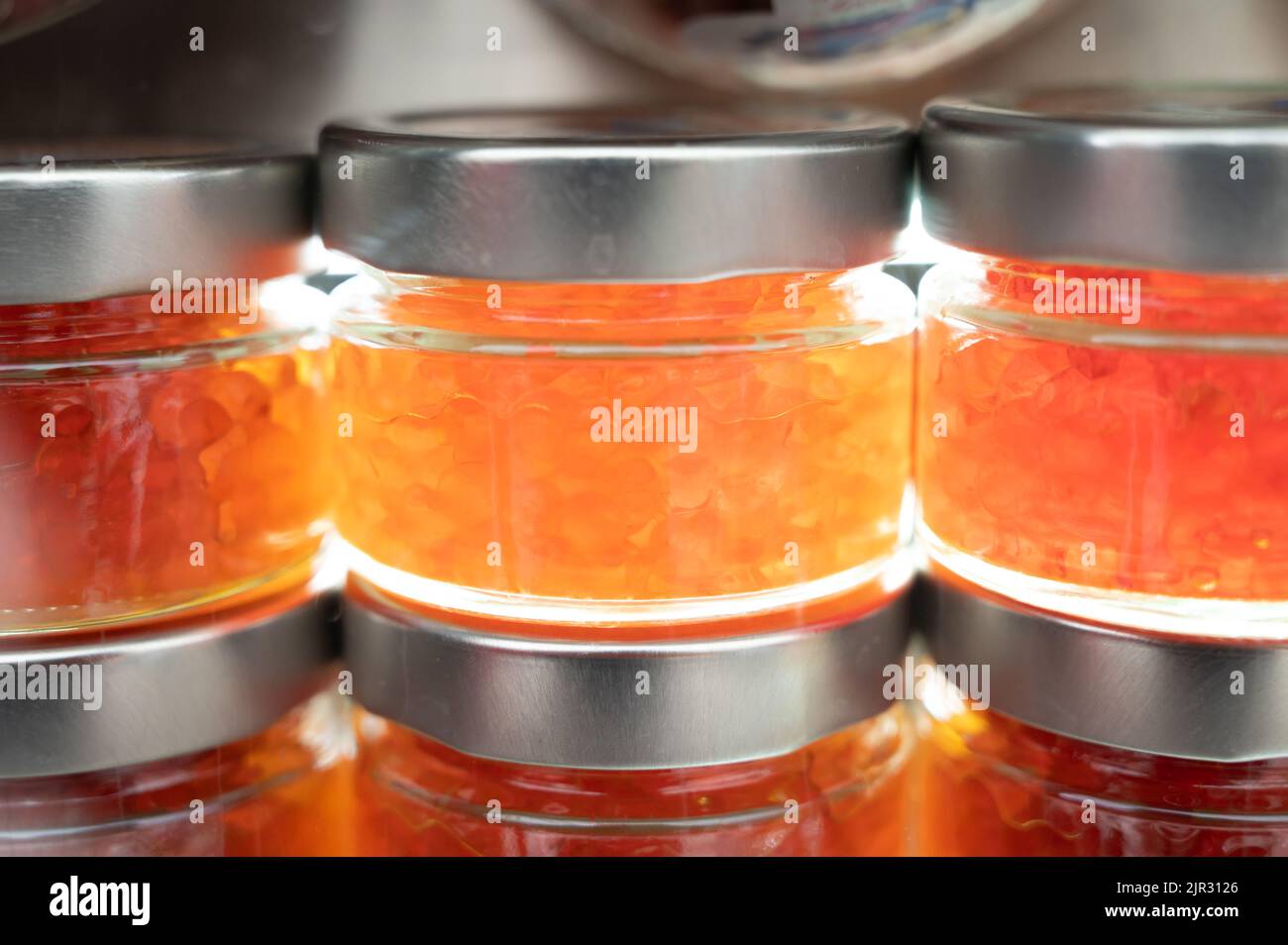 Small glass cans with real fish salmon and trout red, orange and yellow ...