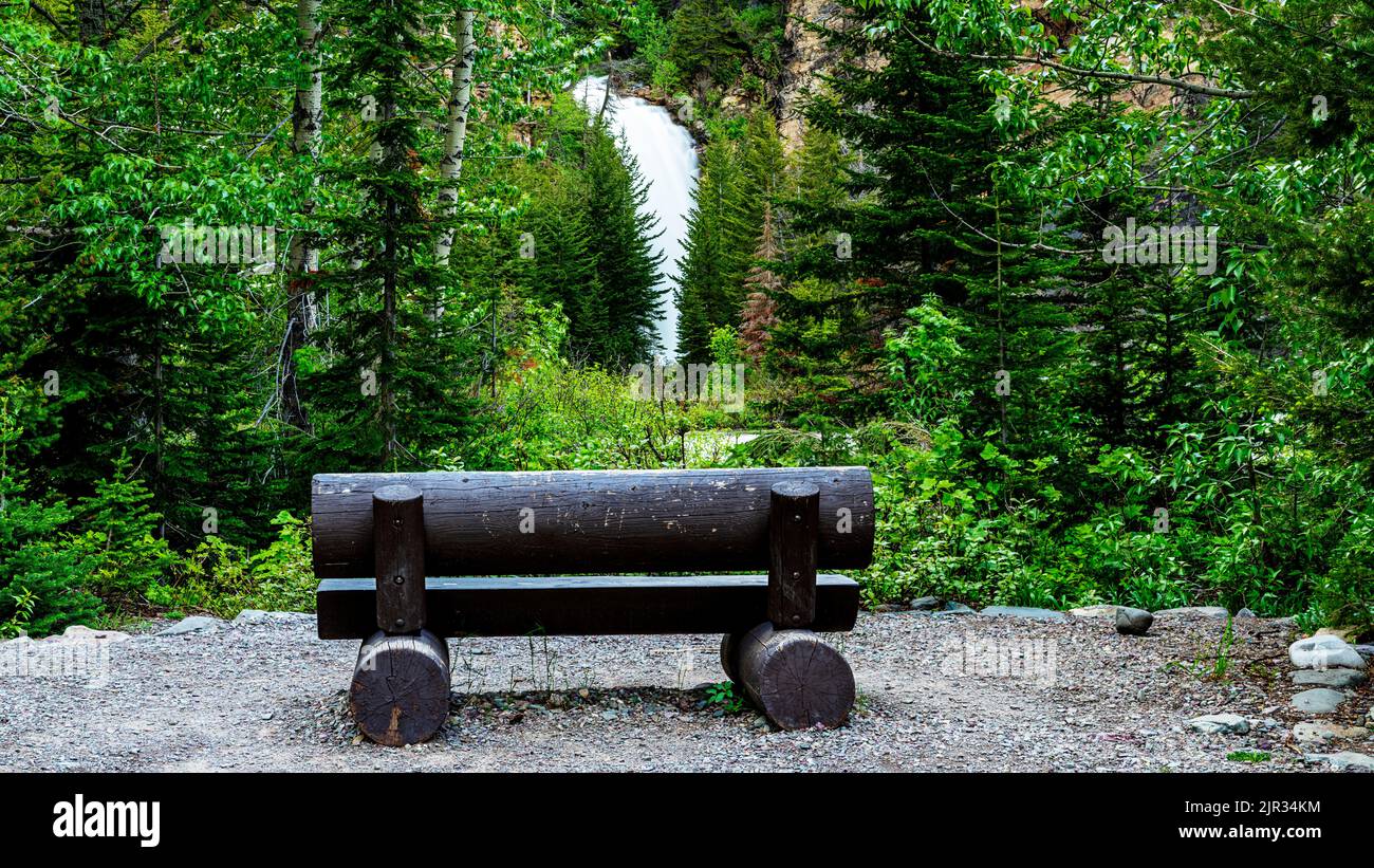 Glacier Park resting bench with a view of a waterfall Stock Photo