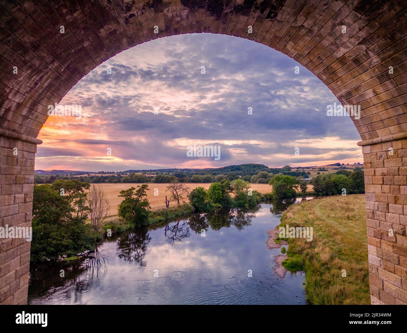 UK Weather: Beautiful eerial view of the sunset over the Yorkshire countryside and the River Wharfe viewed through an arch of Arthington Viaduct. Stock Photo