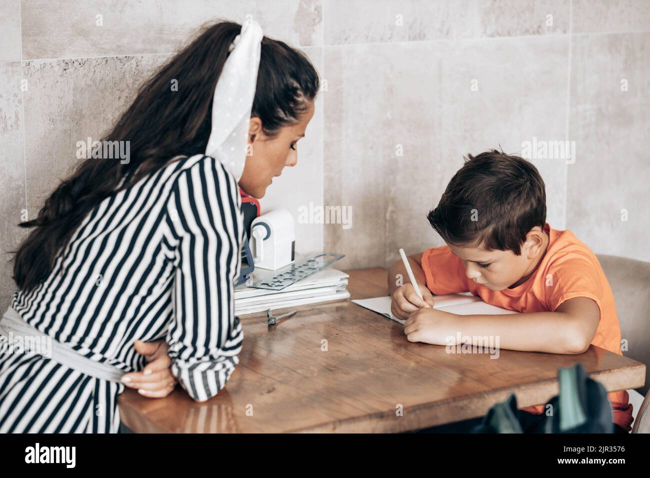 Little school boy doing homework with spring divider, sitting at the table Stock Photo