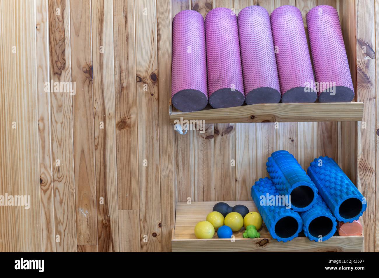 Assorted foam rollers and other utensils in a gym with wooden shelves Stock Photo