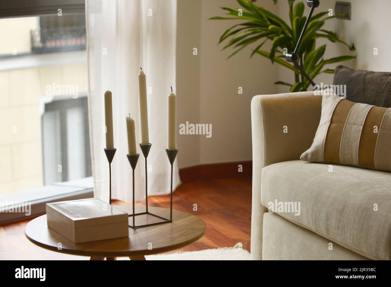 corner of a living room with a bay window, a round wooden side table ...