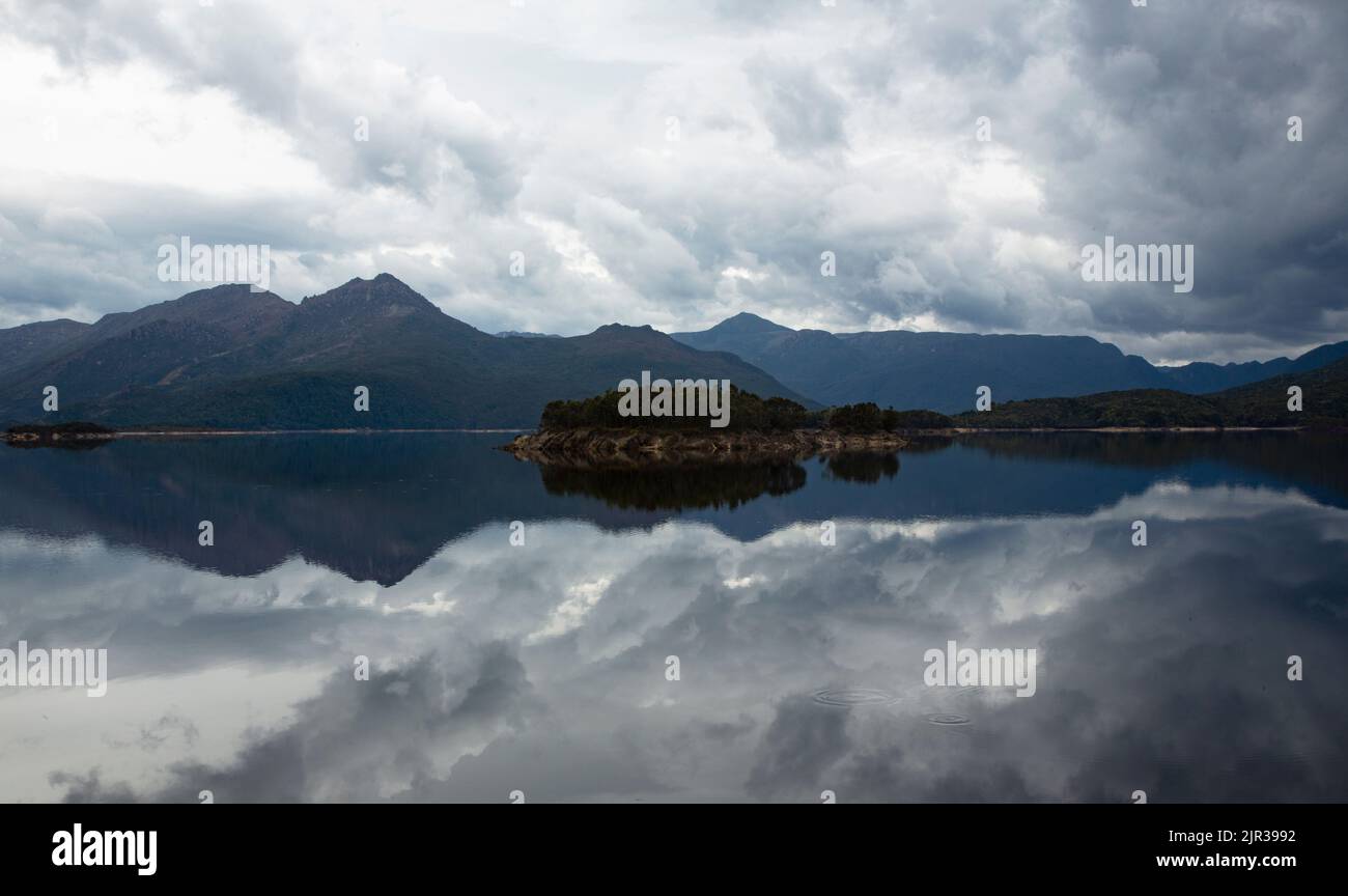 Wild beauty of billowing clouds and mountains reflect in Lake Burbury, a green energy hydro impoundment in Tasmania, Australia Stock Photo