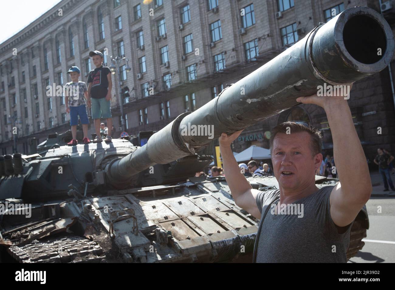 A man poses for a photo next to a destroyed Russian tank displayed on the main street Khreshchatyk as part of the upcoming celebration of the Independence Day of Ukraine amid Russia's invasion of Ukraine in central Kyiv. Stock Photo