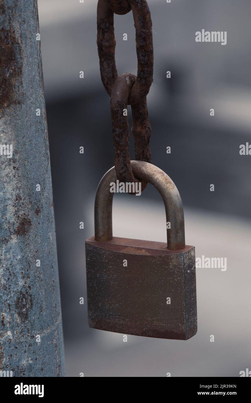 Locked padlock hanging from a rusty chain Stock Photo