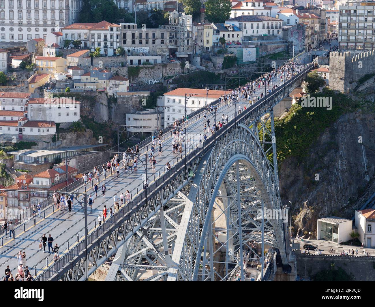 View over Luis I bridge In Porto, Portugal, with buildings behind. People walk along the bridge which is also used by the metro train. Stock Photo