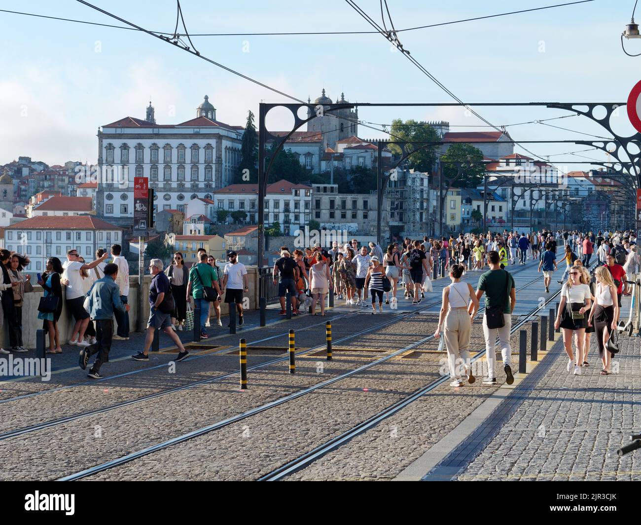 Luis I bridge In Porto, Portugal, with buildings behind. People walk along the bridge which is also used by the metro train, hence the tracks. Stock Photo