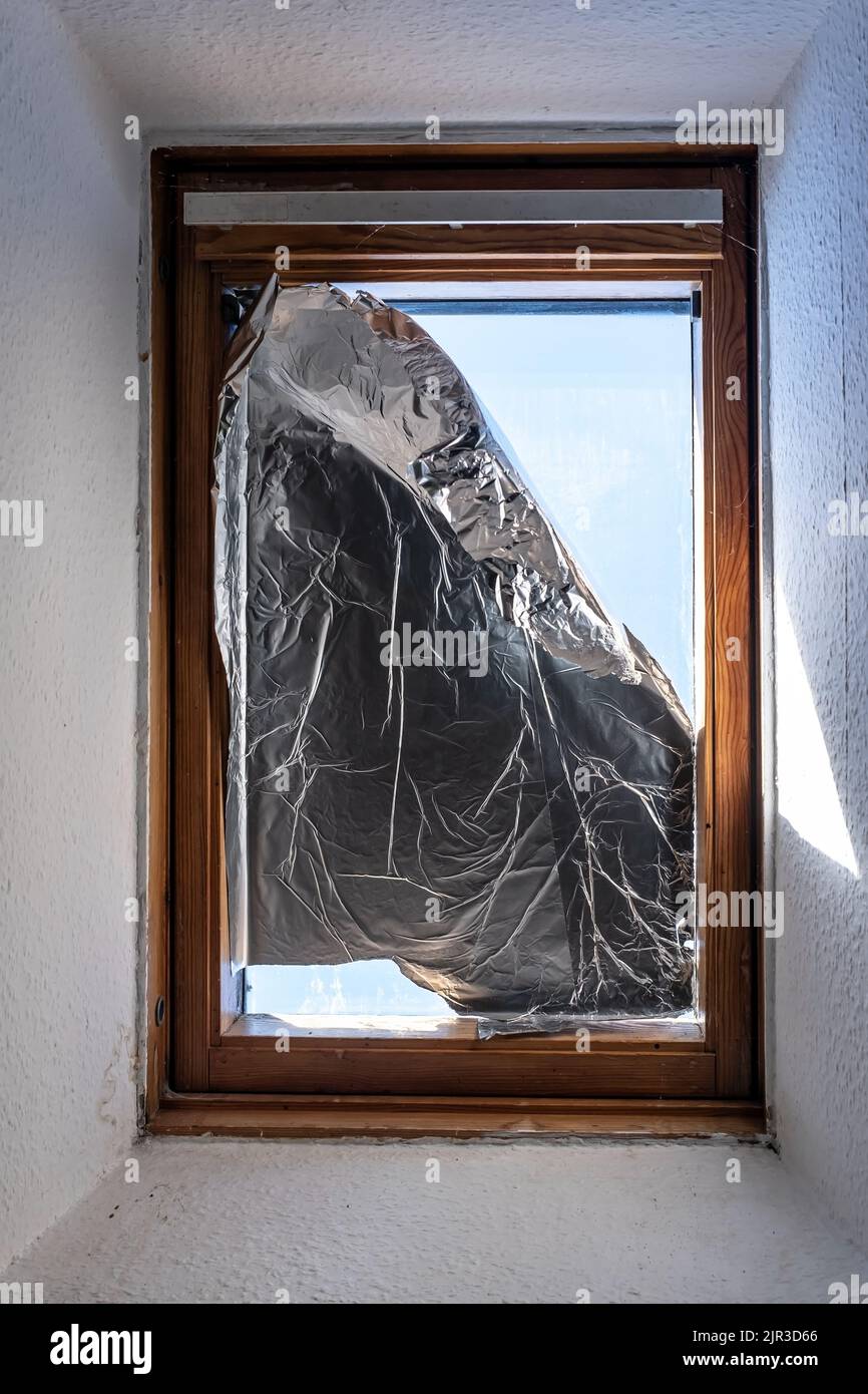 Window covered with foil to prevent sunlight from entering house during