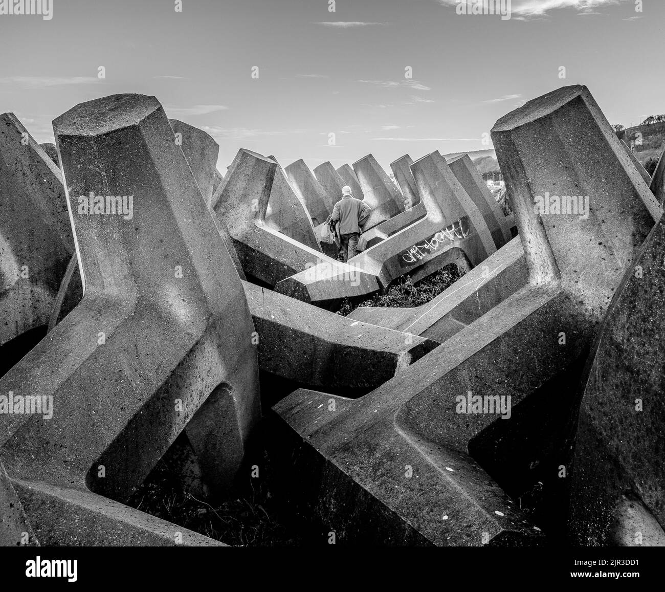 A monochrome image of concrete ramparts with a bald-headed man in the