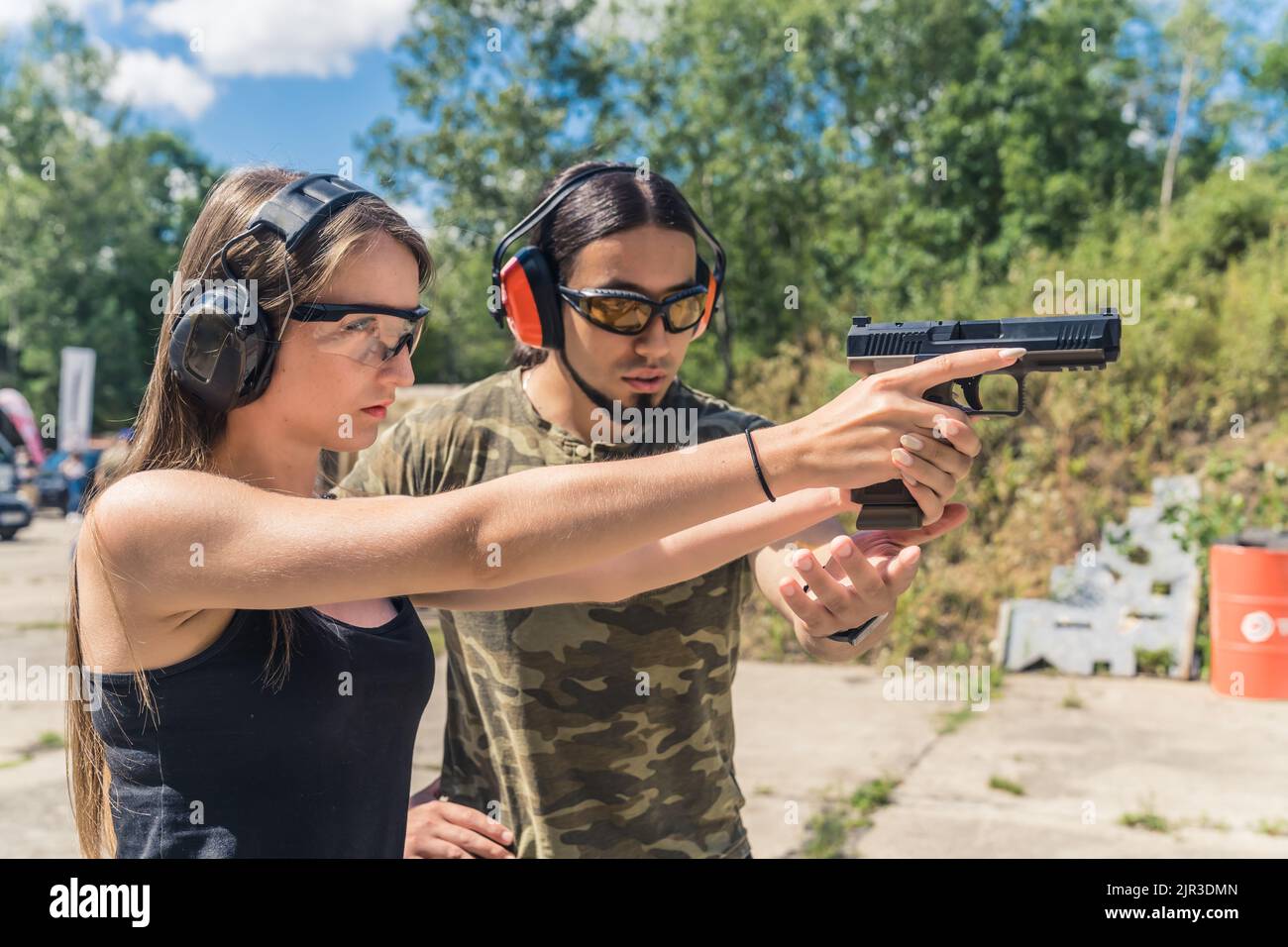 Male instructor showing female client how to aim handgun. Safety