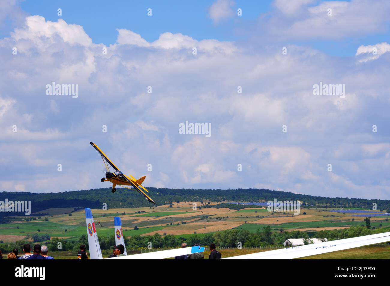 Single engine yellow air plane flying at low altitude close to the ground Stock Photo