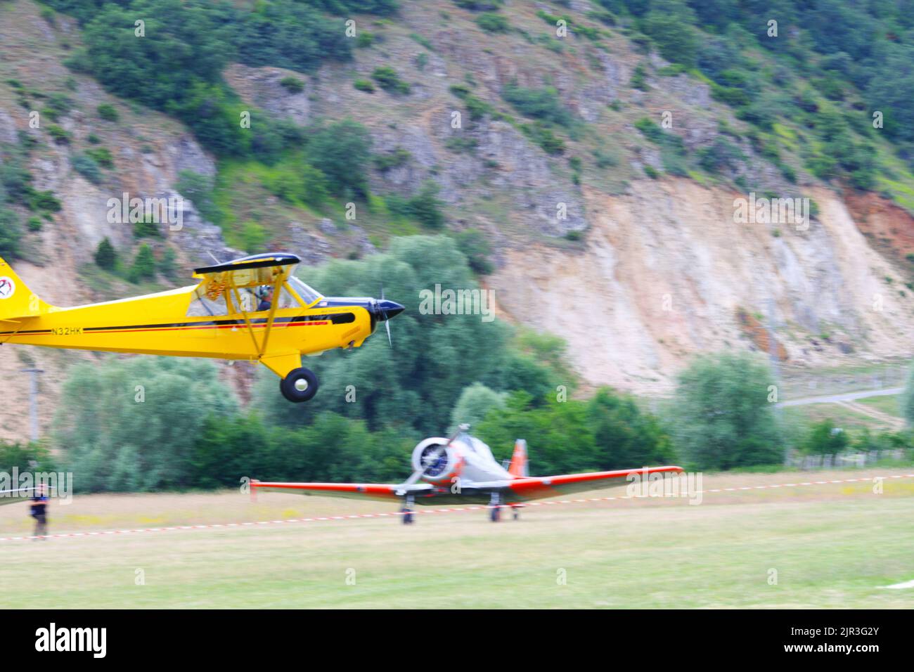Single engine yellow air plane flying at low altitude close to the ground Stock Photo
