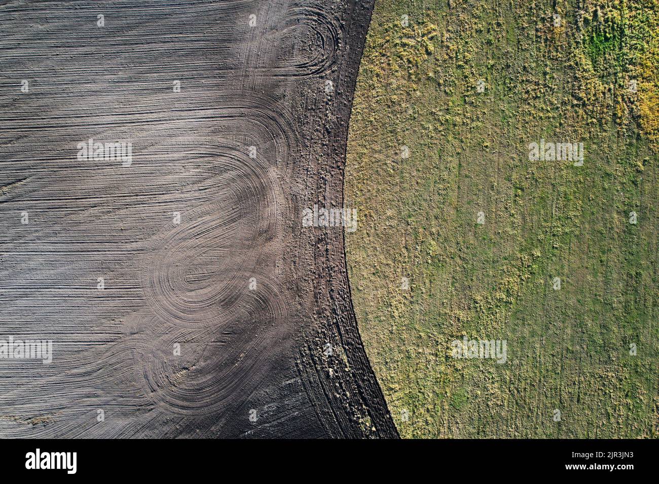 Uncultivated field with grass and dark agriculture meadow aerial drone top view Stock Photo