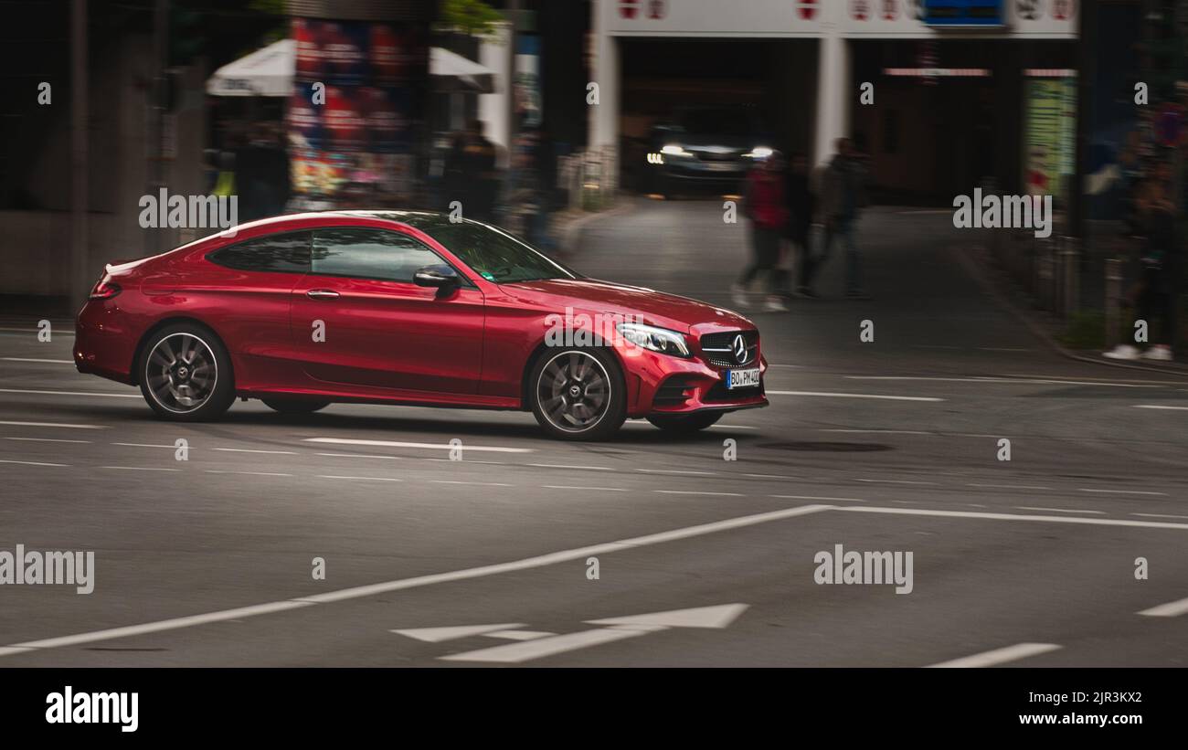 A modern red Mercedes Benz C class coupe (C205) driving on an intersection in Bochum, Germany Stock Photo