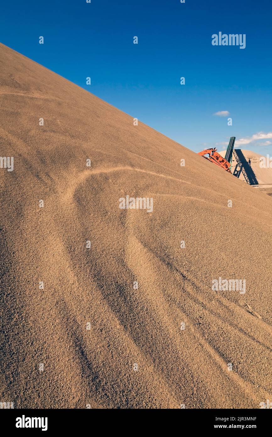Mound of sand and machinery in a commercial sandpit. Stock Photo