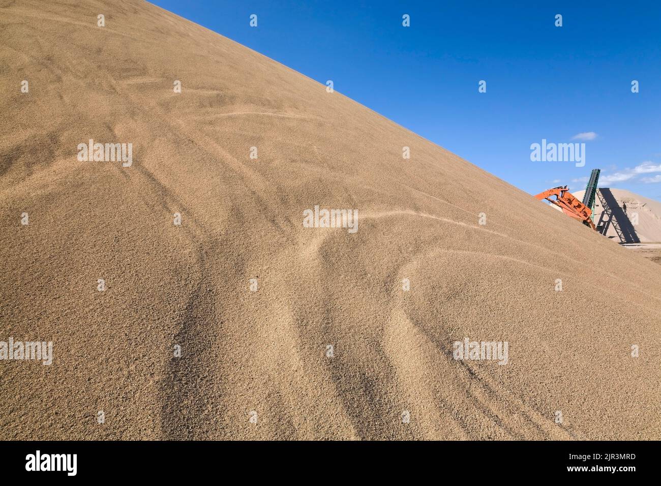 Mound of sand and machinery in a commercial sandpit. Stock Photo