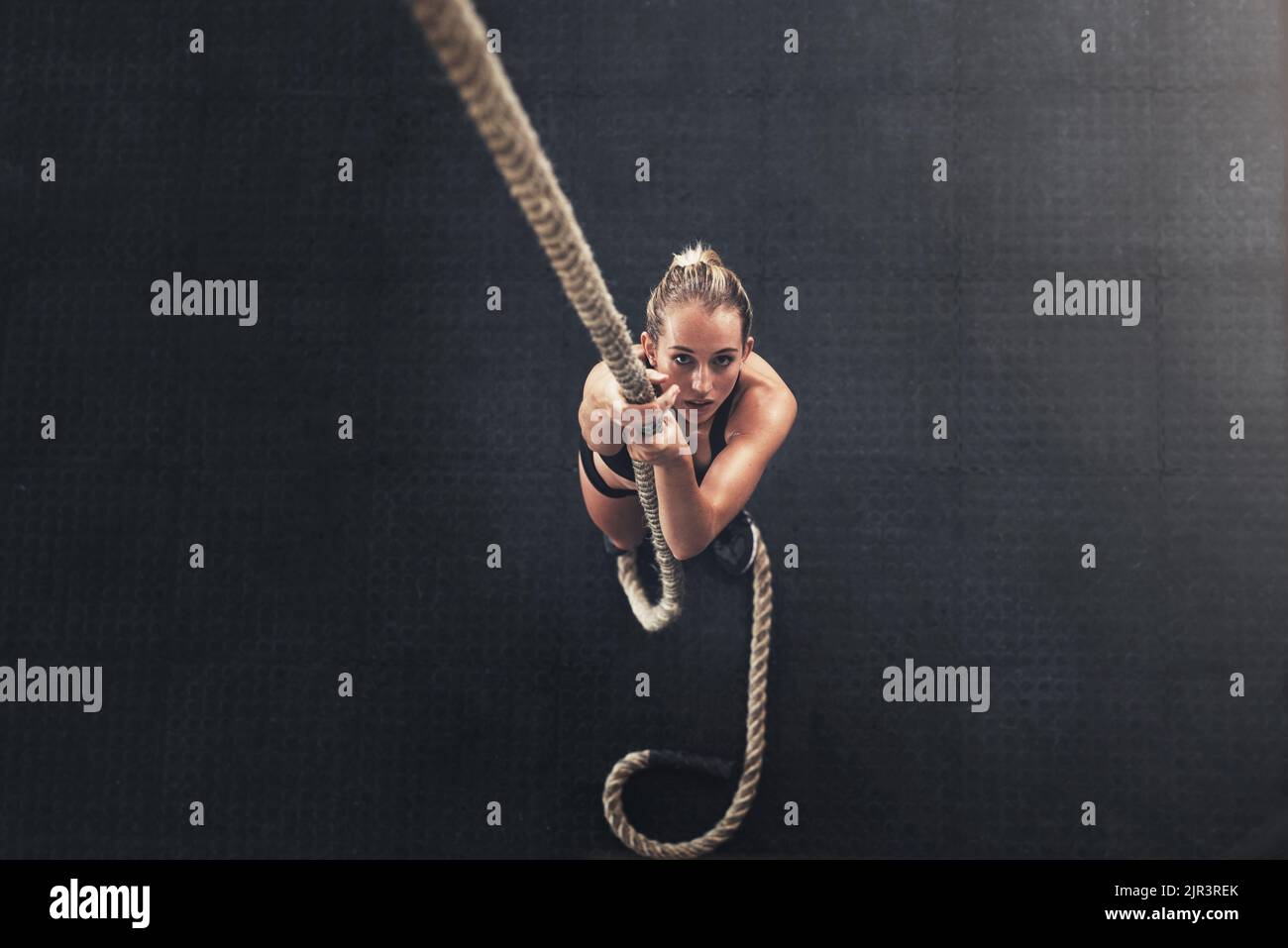 You cant go wrong with strong. a sporty young woman climbing a rope in