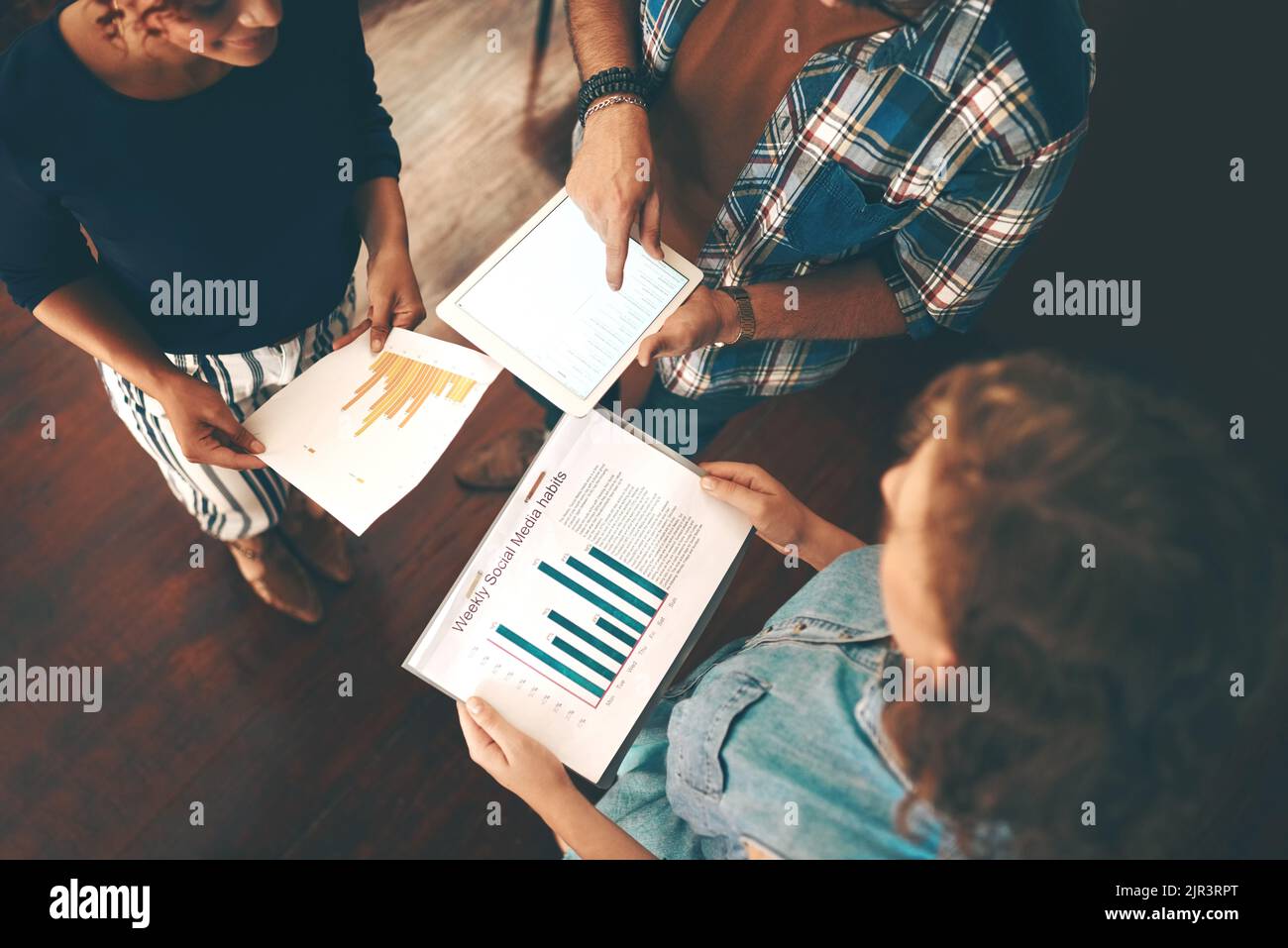 Reviewing all the info theyve gathered. High angle shot of a group of businesspeople analyzing graphs in an office. Stock Photo