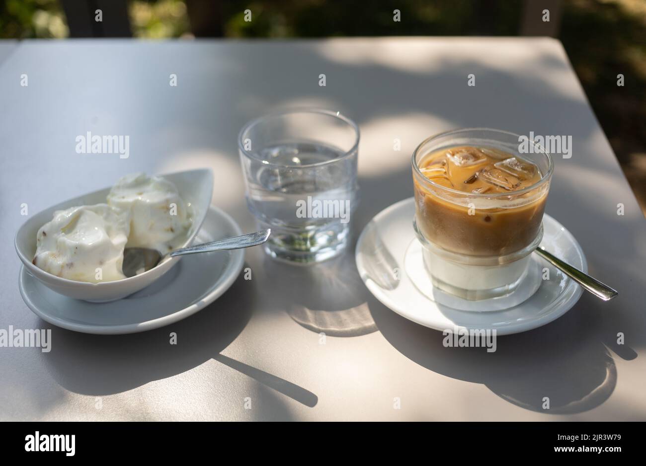 https://c8.alamy.com/comp/2JR3W79/glass-of-iced-coffee-on-the-table-at-summer-terrace-2JR3W79.jpg