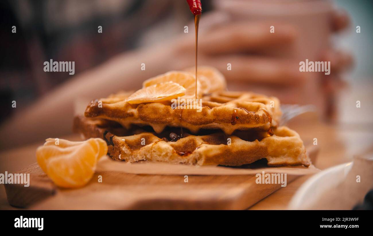Covering a belgian waffle with a syrup - cafe kitchen Stock Photo