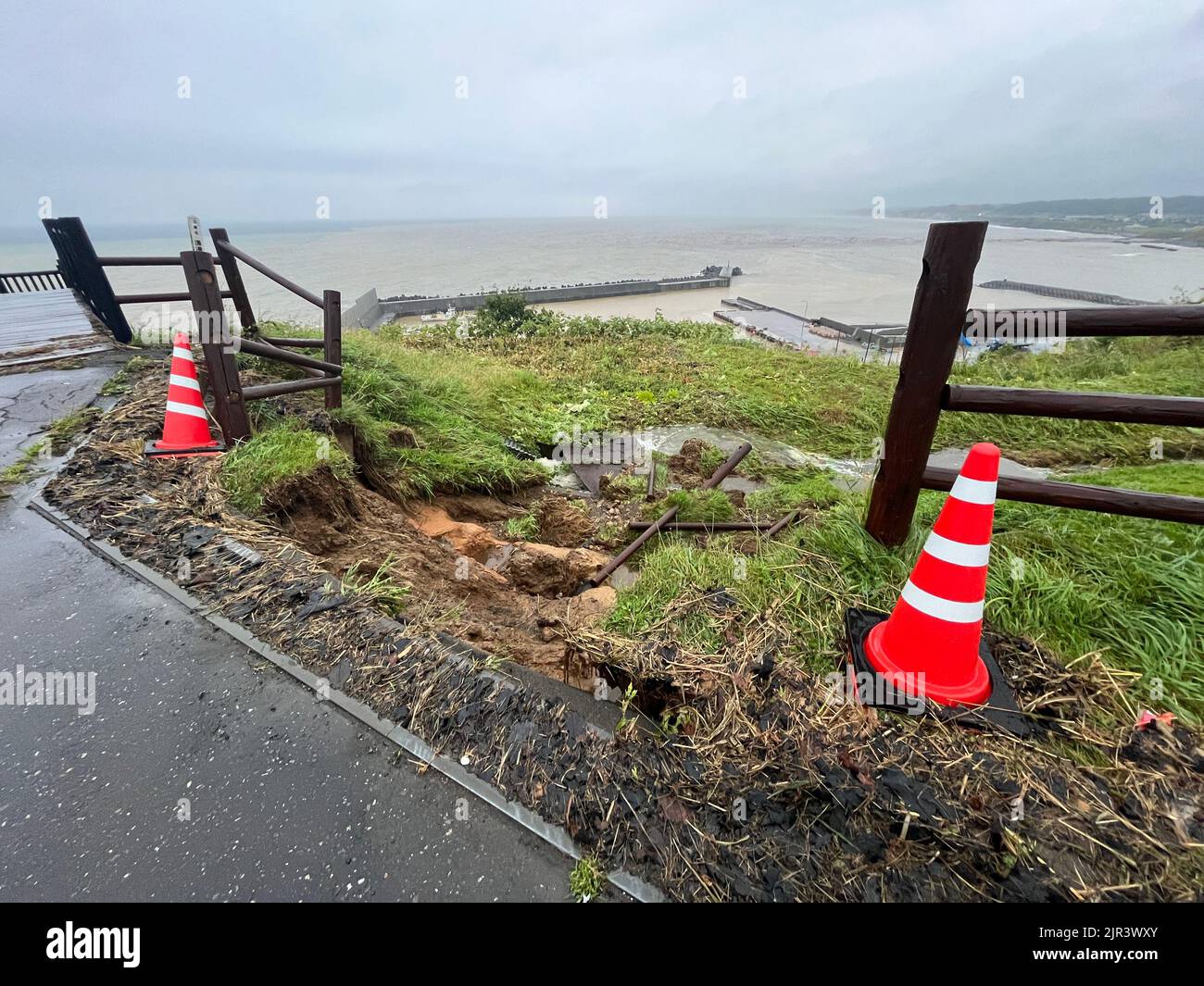 Orange cones by a fence and small landslide Stock Photo