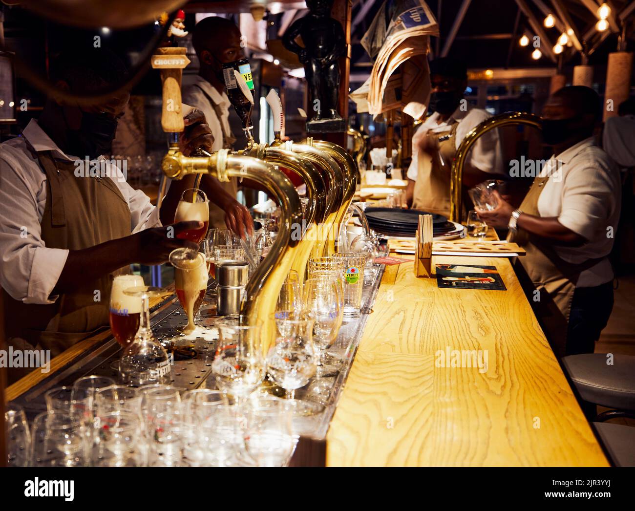A male bartender pouring beer on grasses to serve to customers in a bar in Cape Town,  South Africa Stock Photo