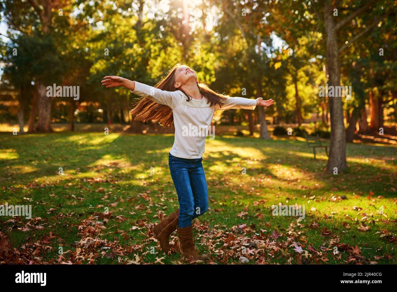 Leaf it to kids to make the most of life. a happy little girl playing in the autumn leaves outdoors. Stock Photo