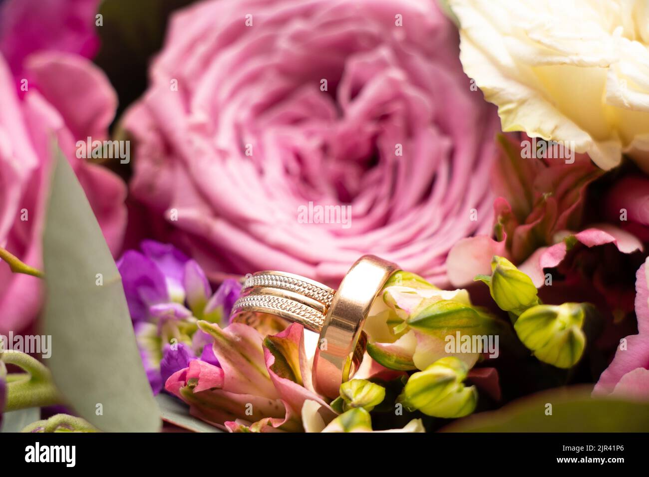 wedding gold rings of the bride and groom lie on the background of a bouquet of flowers of the bride, gold rings at the wedding Stock Photo