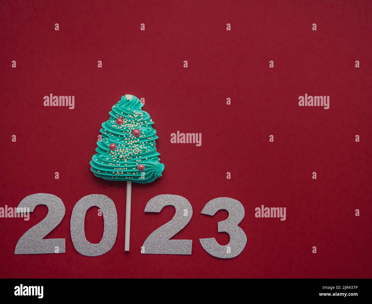 2023 and blue candy in the form of a Christmas tree on a red background Stock Photo