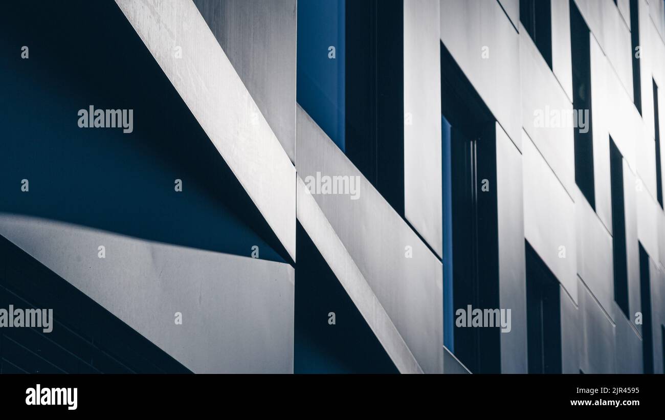 The walls of a futuristic modern building in a city with sunlight reflecting on the surface