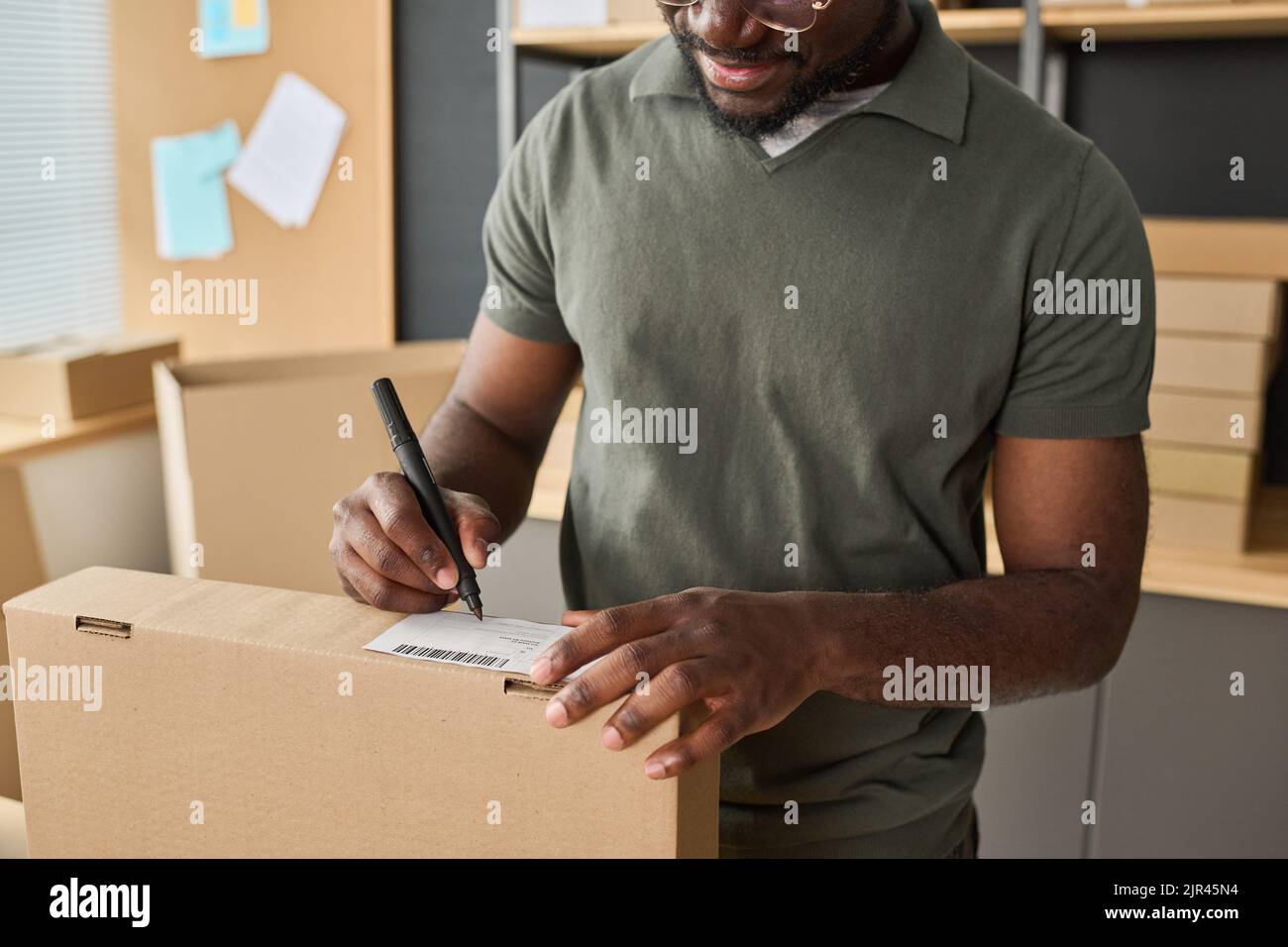Close-up of African man signing parcel before shipping while working in warehouse Stock Photo
