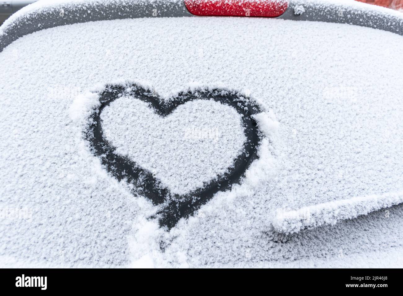 Snow heart on the car window with copy space. Heart sign in fresh snowflakes. Heart shape symbol drawn on snowed car glass. Love concept. Valentine's Stock Photo