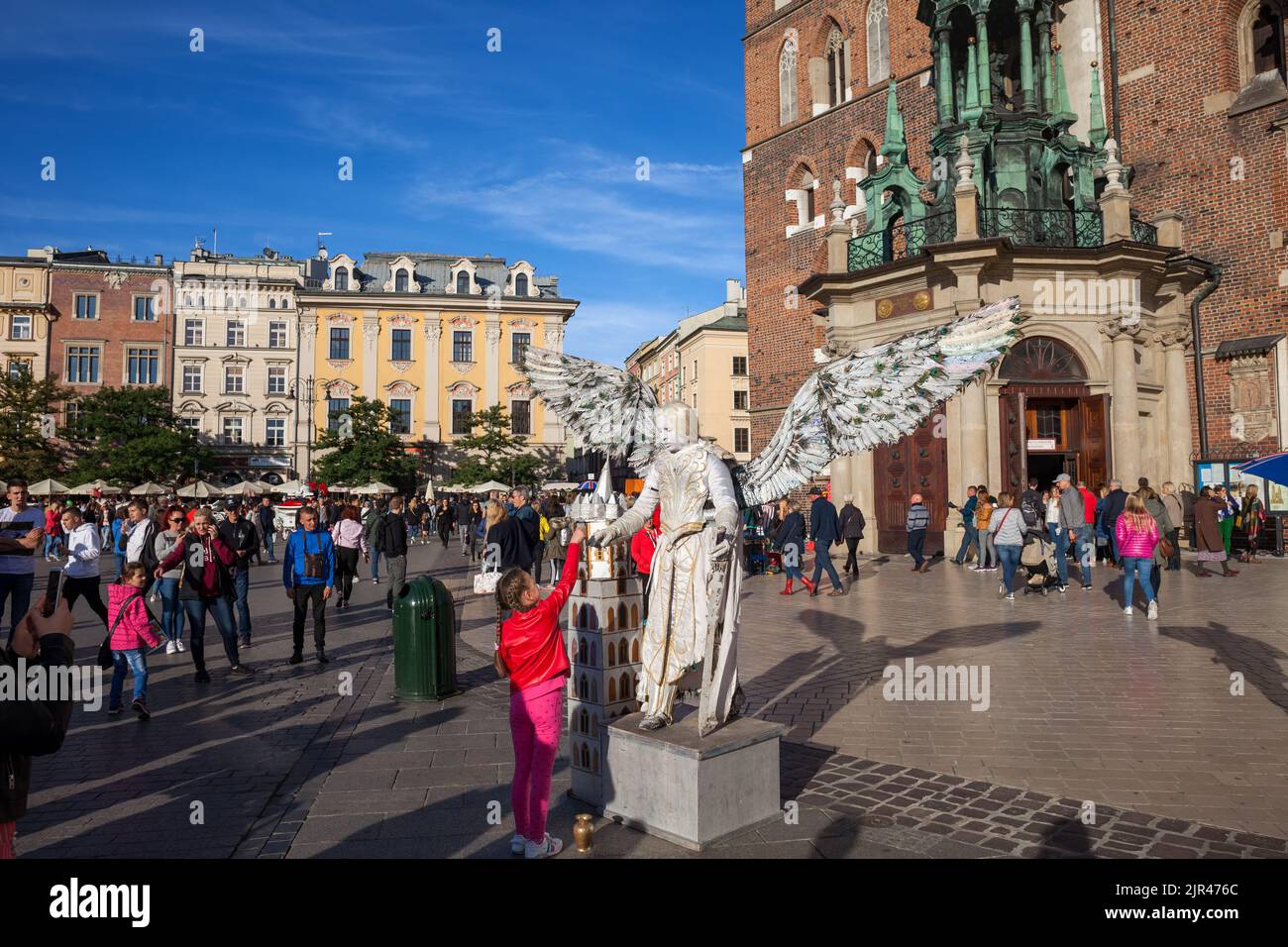 Krakow (Cracow), Poland - September 30, 2018: Group of people and child giving money to angel mime on lively main square in the Old Town in front of S Stock Photo